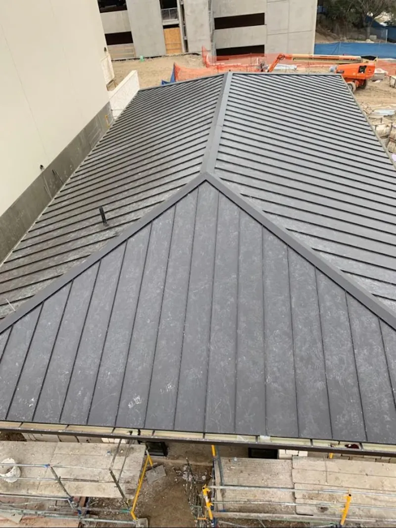 Commercial metal roof construction with crane equipment in Danvers